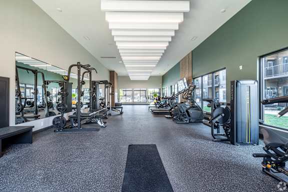 A spacious gym with a variety of equipment and a long mirrored wall.