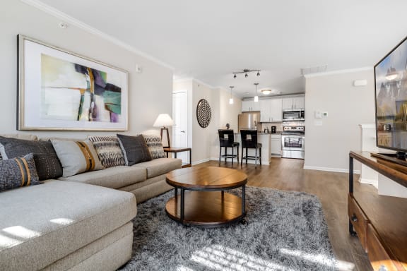 a living room with a couch coffee table and a kitchen in the background