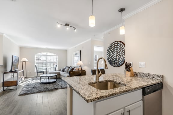 a kitchen island with granite countertops in front of a living room with a couch and a