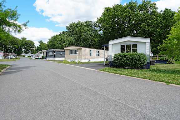 A street view of a mobile home park with several homes and trees.