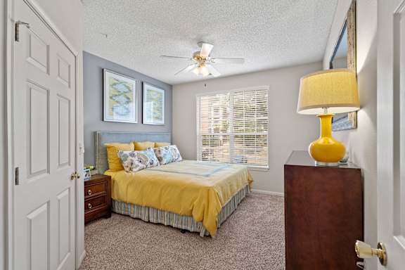 A bedroom with a bed, dresser, and ceiling fan.