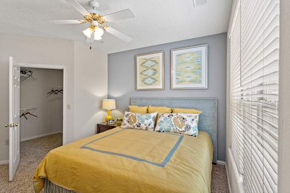 A bedroom with a yellow bed and a ceiling fan.