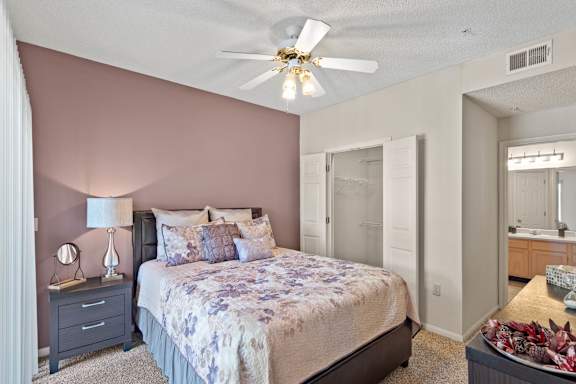 A bedroom with a bed, nightstand, and a ceiling fan.