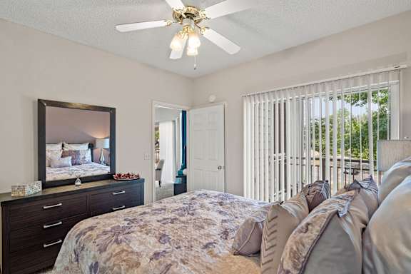 A bedroom with a bed, dresser, and a ceiling fan.