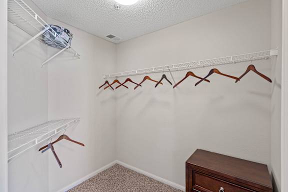 A white closet with a fan and a brown dresser.