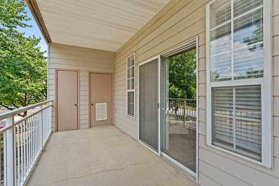 A balcony with a sliding glass door and a brown door.