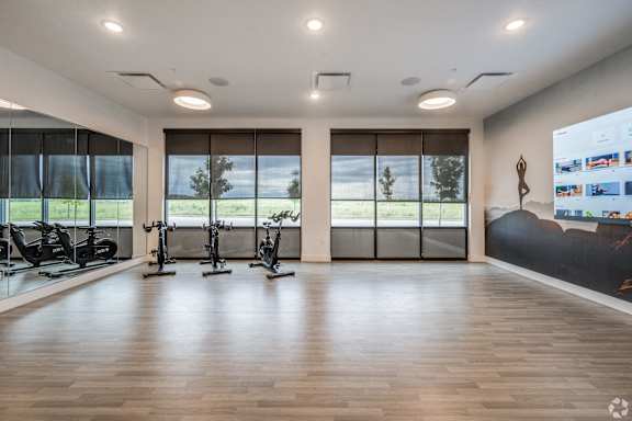 A spacious gym with wooden floors and a variety of exercise equipment.