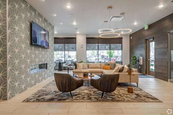 A modern living room with a large sofa, a TV, and a patterned wallpaper.