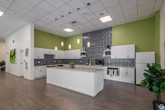 A kitchen with white cabinets and a green wall.