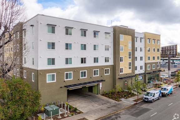 A street view of a multi-story building with a parking garage underneath.