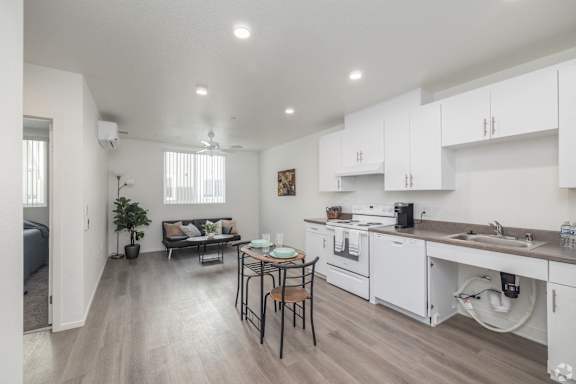 A kitchen with white cabinets and a dining table with chairs.