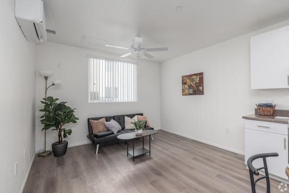 A living room with a couch, a chair, a potted plant, and a painting on the wall.