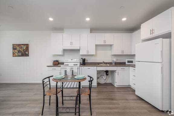 A kitchen with white cabinets and a table set for two.