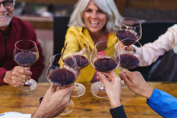 A group of people toasting with glasses of red wine.