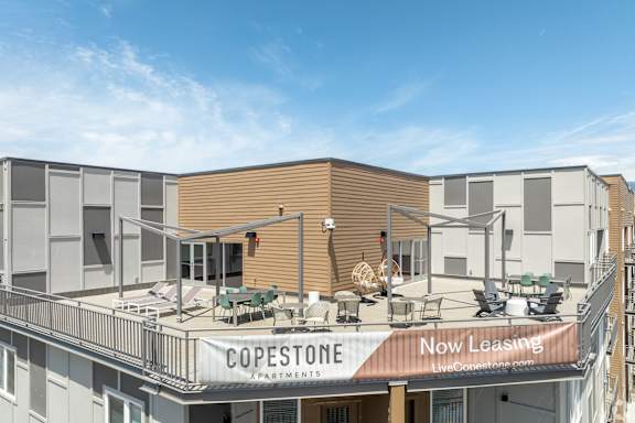 A building with a sign that says "COPESTONE Apartments" and "Now Leasing" is shown.