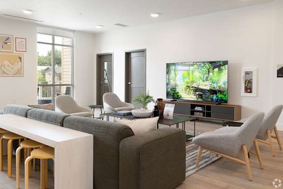 A modern living room with a grey sofa, a white table, and a television.