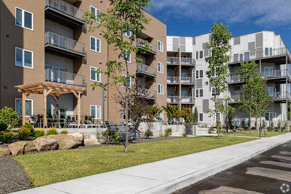 Apartment buildings with balconies and trees in front.