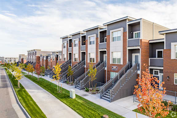 a row of townhomes with stairs and grass and trees