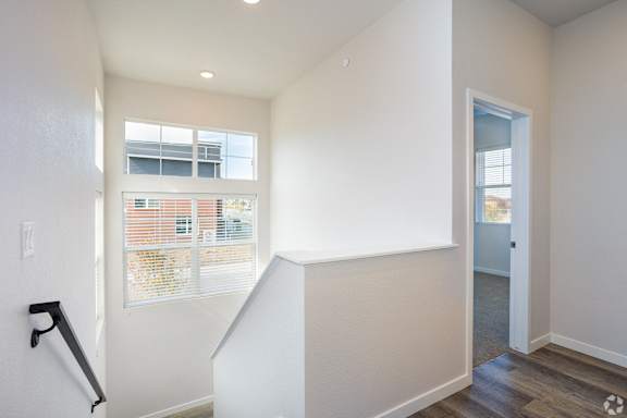 a renovated living room with white walls and a window and a staircase