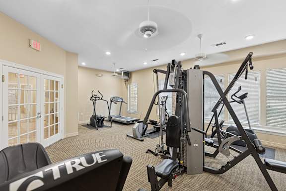 A gym with a variety of equipment including treadmills, elliptical machines, and weight machines.