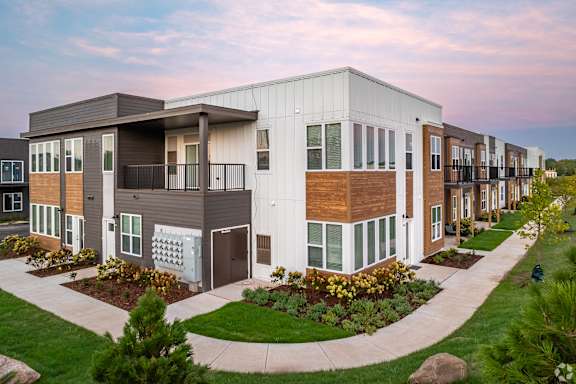 A modern apartment complex with a landscaped courtyard in front.