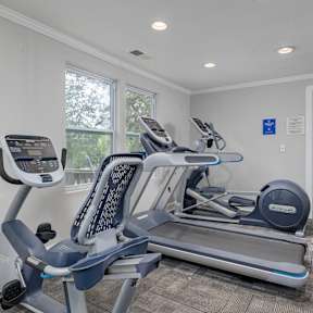 A gym with a treadmill and elliptical trainer.