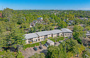 A large building surrounded by trees and a parking lot.