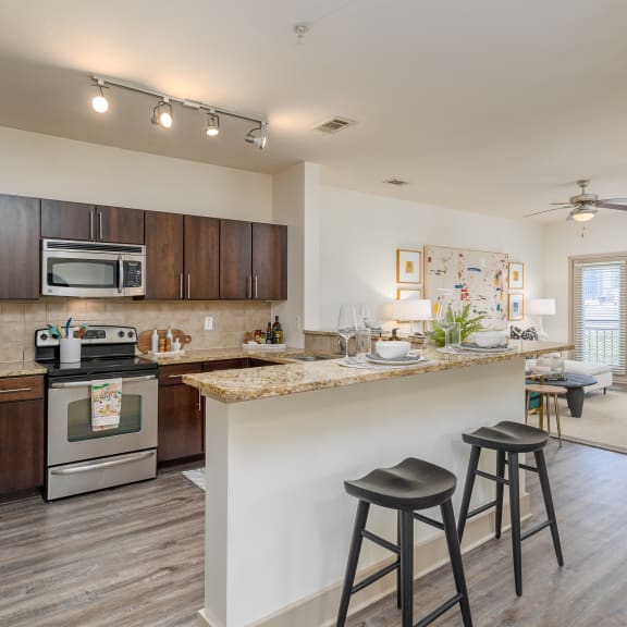 an open kitchen and living room with a bar and stools