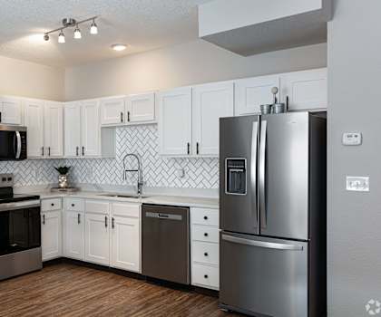 A kitchen with white cabinets and a black fridge.