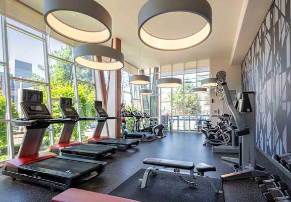 a gym with cardio equipment and windows in the lobby of a building