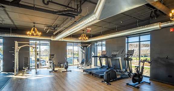 a gym with fitness equipment and windows in a building with wood floors