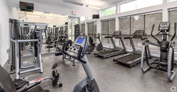 a gym with cardio equipment and weights in a building with windows