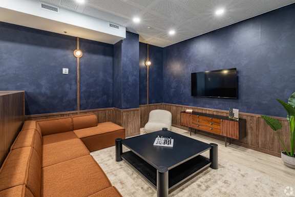 A modern living room with a brown sofa, a black coffee table, and a flat-screen TV mounted on the wall.