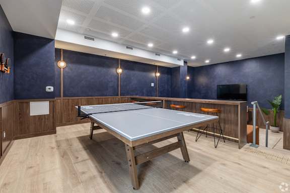 A ping pong table is in the middle of a room with wooden floors and walls.
