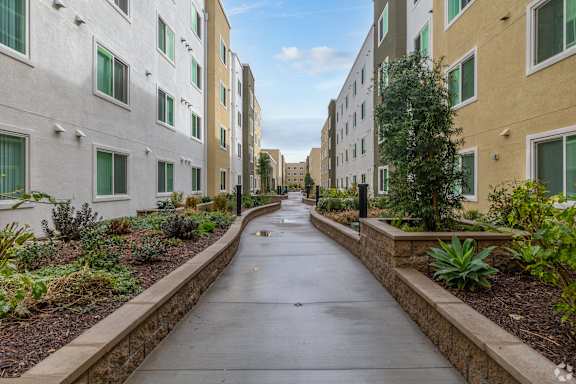 A long, narrow walkway separates two rows of apartment buildings.