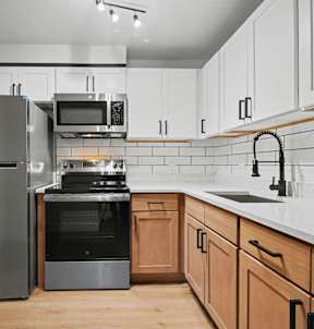 A modern kitchen with a stainless steel refrigerator, microwave, oven, and sink.