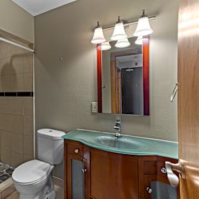 A bathroom with a toilet, sink, and mirror.