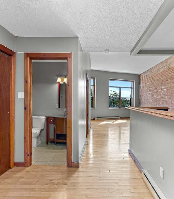 A long hallway with a doorway leading to a bathroom.