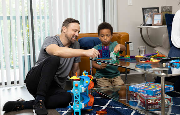 A man and a boy are playing with a toy set on a table.