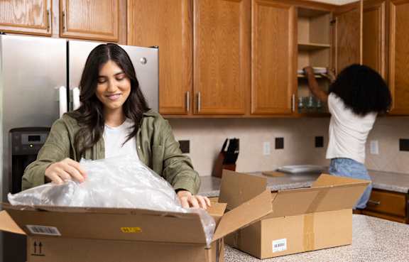 A woman is unpacking a box in a kitchen.