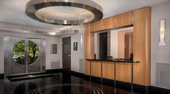 A modern hallway with a glass door and a wooden panel wall.