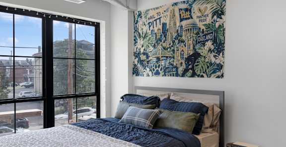 A bedroom with a large bed and a large tapestry hanging on the wall.