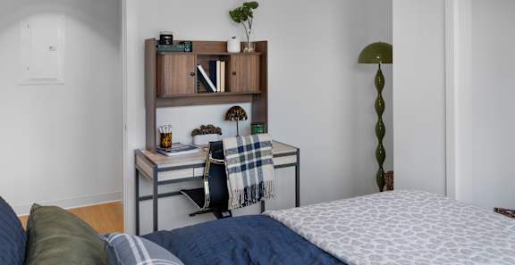 A bedroom with a bed, desk, and chair.