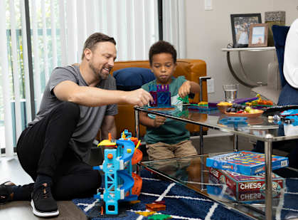 A man and a boy are playing with a toy set on a table