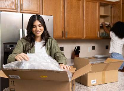 A woman is unpacking a box in a kitchen.