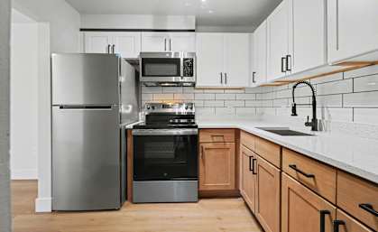 A modern kitchen with a stainless steel refrigerator, microwave, oven, and sink.