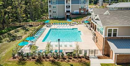 A large swimming pool surrounded by a fence and trees.