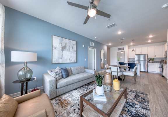 A modern living room with a grey sofa, a coffee table, and a ceiling fan.