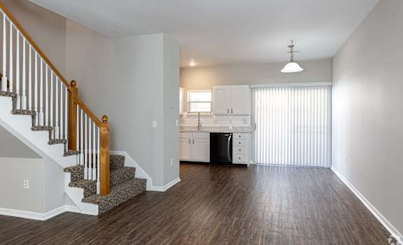 A kitchen with white cabinets and a dishwasher is visible through a window.