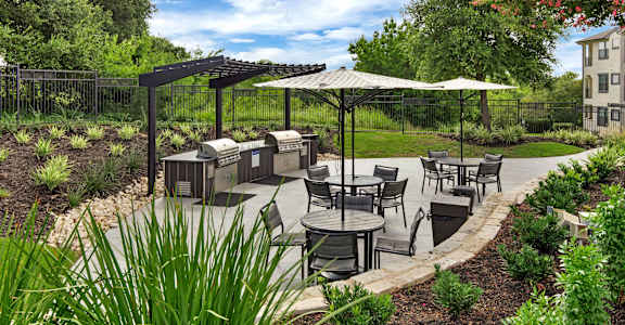 a patio with tables and umbrellas and barbecue grills